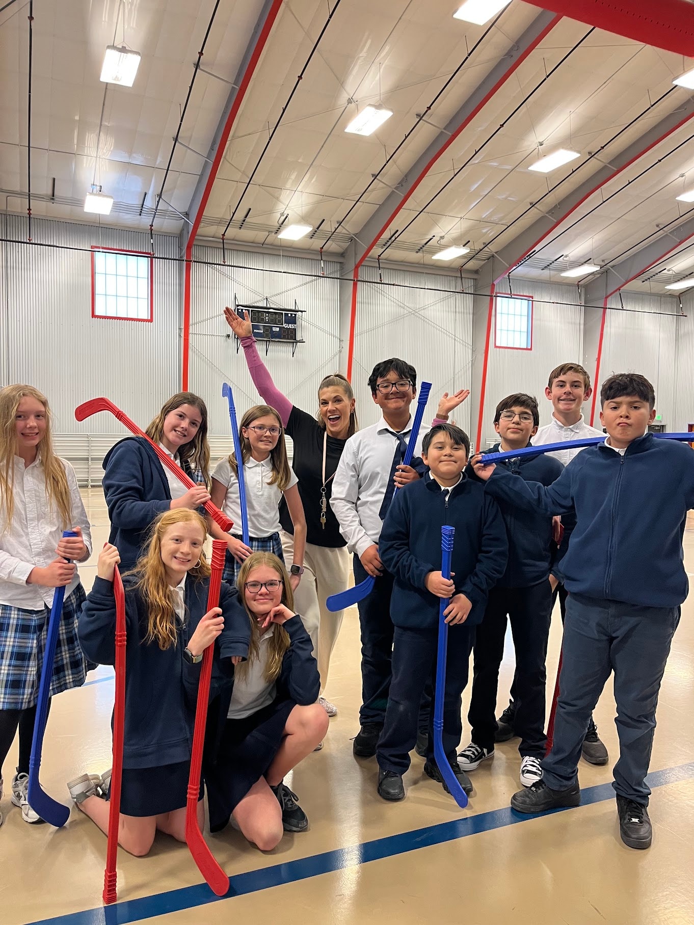 Students playing floor hockey in the gymnasium at Pope John Paul II Academy